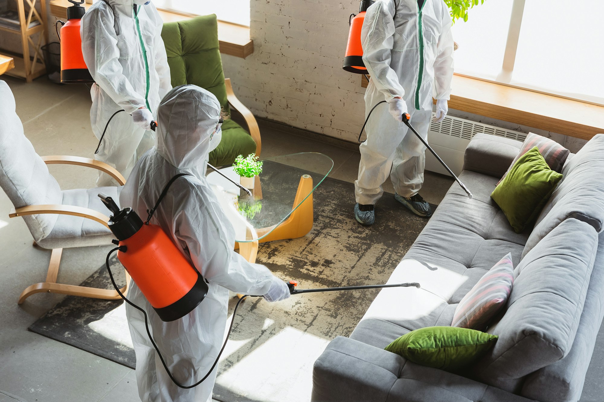 Coronavirus Pandemic. A disinfectors in a protective suit and mask sprays disinfectants in the house